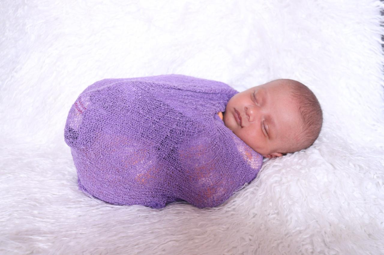 Newborn baby wrapped in a purple blanket